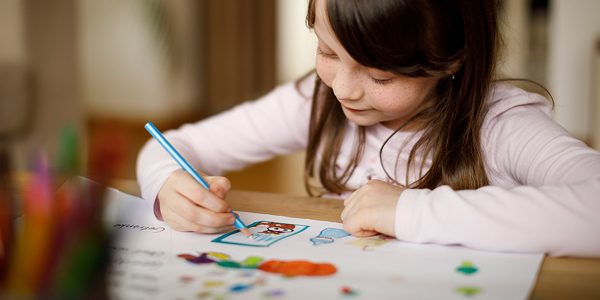 Menina sentada desenhando com lápis de cor