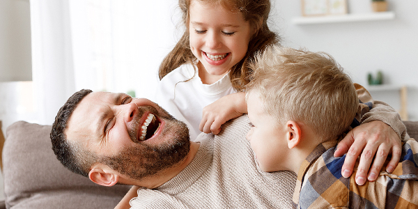 Pai, filho e filha crianças se divertem com gargalhadas e Colégio Alternativo reforça os benefícios da diversão em família