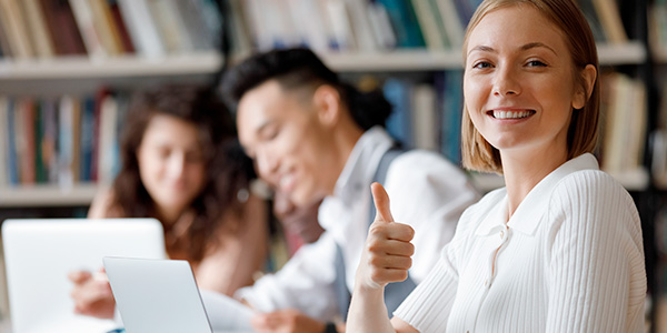 Jovem sorridente faz sinal de joia sobre estudar no exterior usando a nota do Enem. 