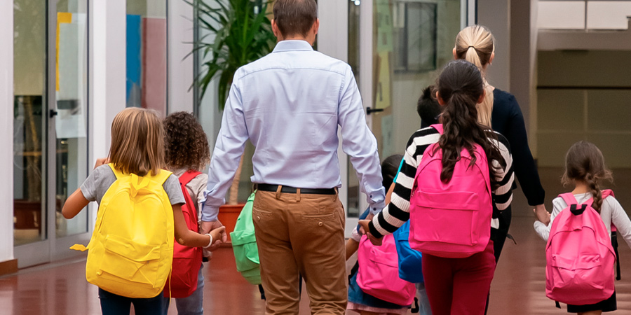 Pais caminhando com os filhos dentro da escola