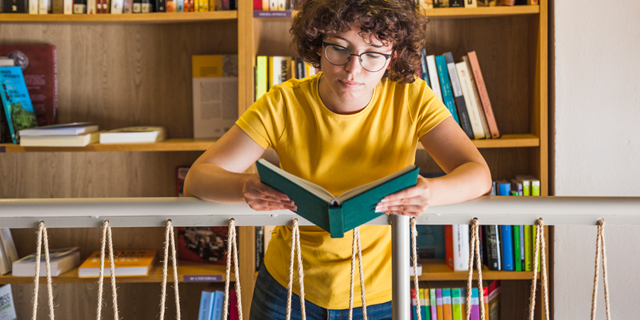 Adolescente lendo livro na biblioteca
