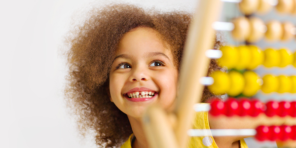 Menina sorrindo em frente a um brinquedo educativo para brincar e aprender