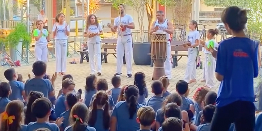alunos vendo apresentação de capoeira 