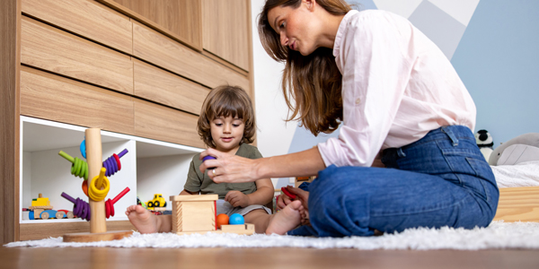 Criança e mãe brincam no chão orientadas pelo Colégio Alternativo para explorar o método Montessori no quarto infantil