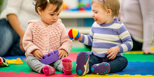 Crianças brincam no chão e o Colégio Alternativo orienta sobre como conduzir o desfralde infantil.