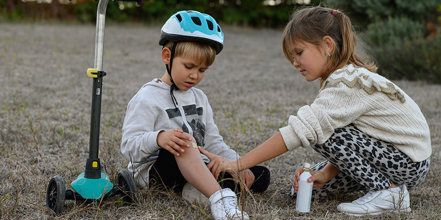 criança ajudando outra que caiu - sabia como os pais constroem resiliência nos filhos desde a infância