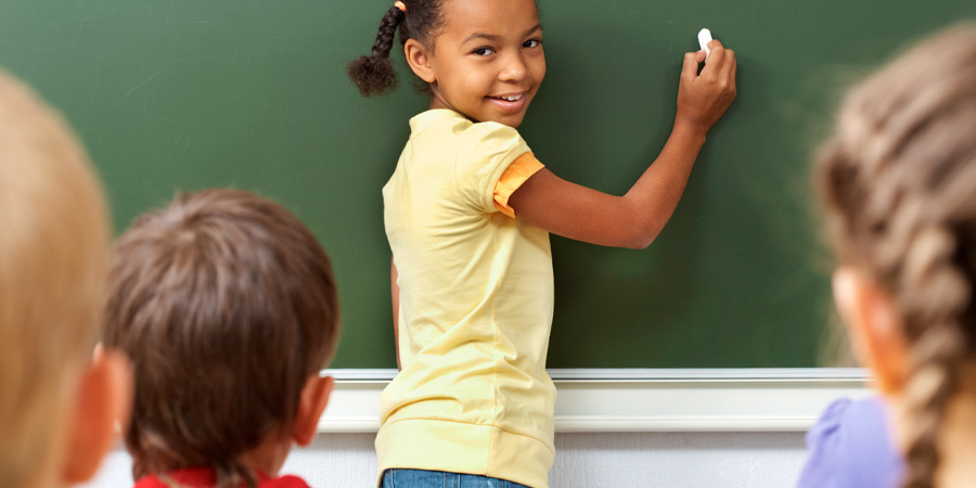 Criança escrevendo na lousa