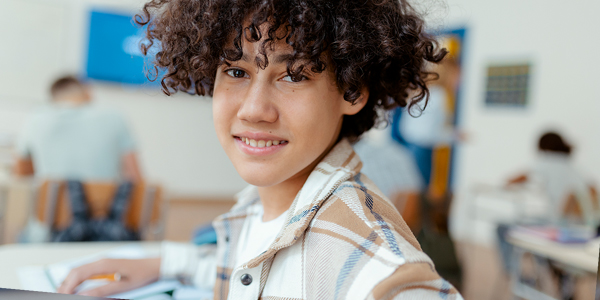 menino entre 11 e 12 anos sorrindo na carteira escolar